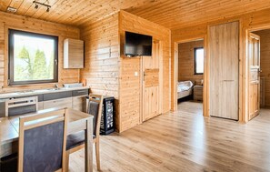 A wooden cabin interior with a kitchen, dining area, and a bedroom. - Awesome home in Darlowo with sauna (Darlowo)