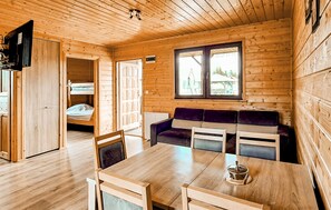 A wooden cabin interior with a dining table, chairs, a sofa, and a bunk bed. - Awesome home in Darlowo with sauna (Darlowo)