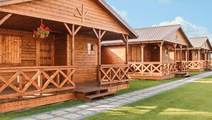 A row of wooden cabins with balconies, a paved walkway, and a clear sky. - Awesome home in Darlowo with sauna (Darlowo)