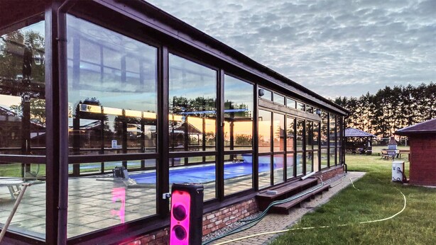 A covered patio with a glass enclosure, a pool, and a barbecue area. - Awesome home in Darlowo with sauna (Darlowo)