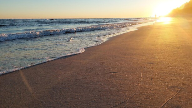 A beach with waves, a clear sky, and the sun setting or rising. - Amazing home in Jaroslawiec with sauna (Jaroslawiec)