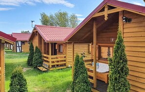 Des cabanes en bois avec des toits rouges, une véranda et un petit jardin.