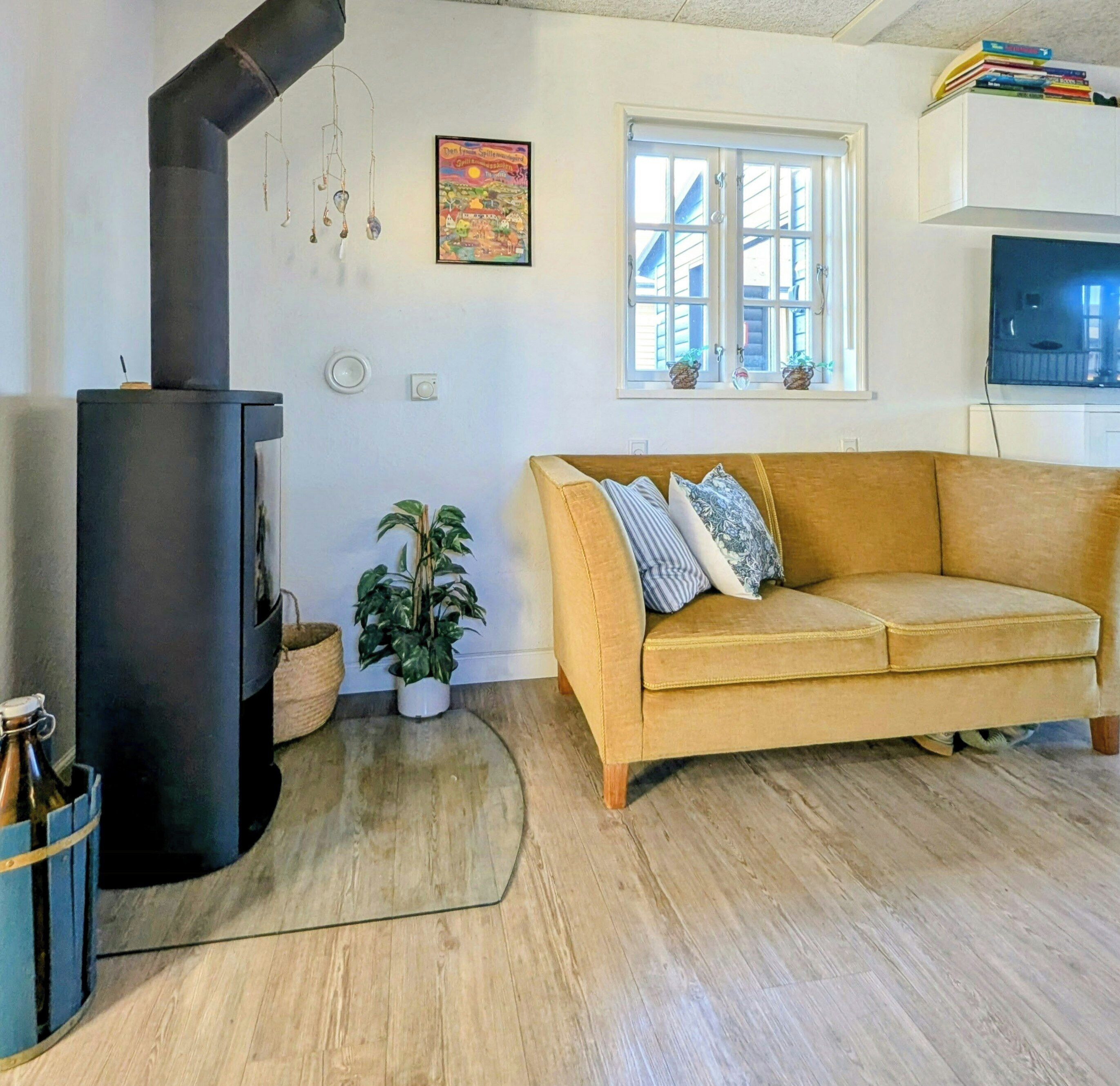 Un salon avec un canapé, une cheminée, une fenêtre et un téléviseur fixé au mur.