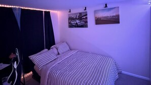 Een slaapkamer met een bed, een bureau en twee foto's aan de muur.
