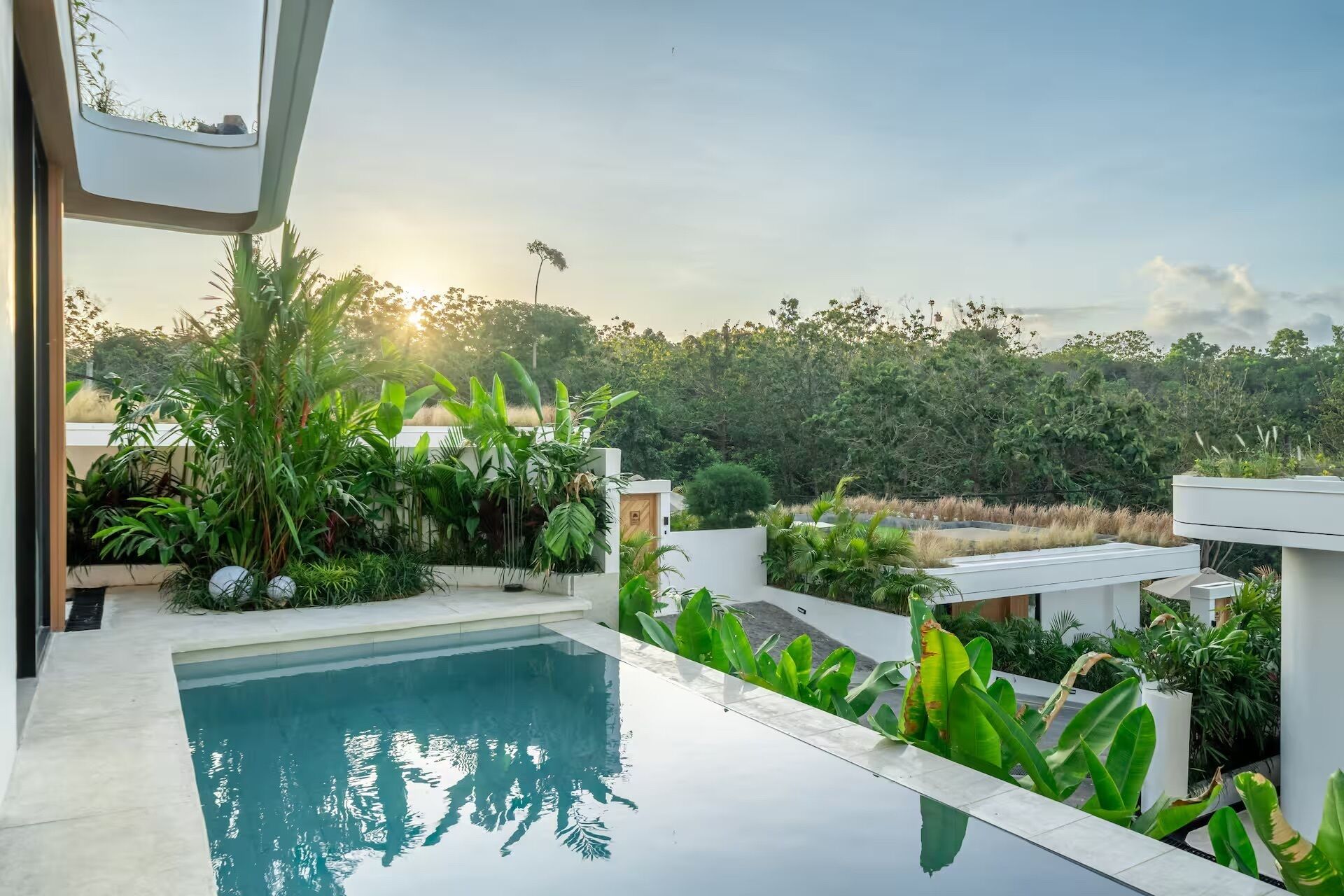 A modern pool area with a clear view of the surrounding greenery and a distant hill.