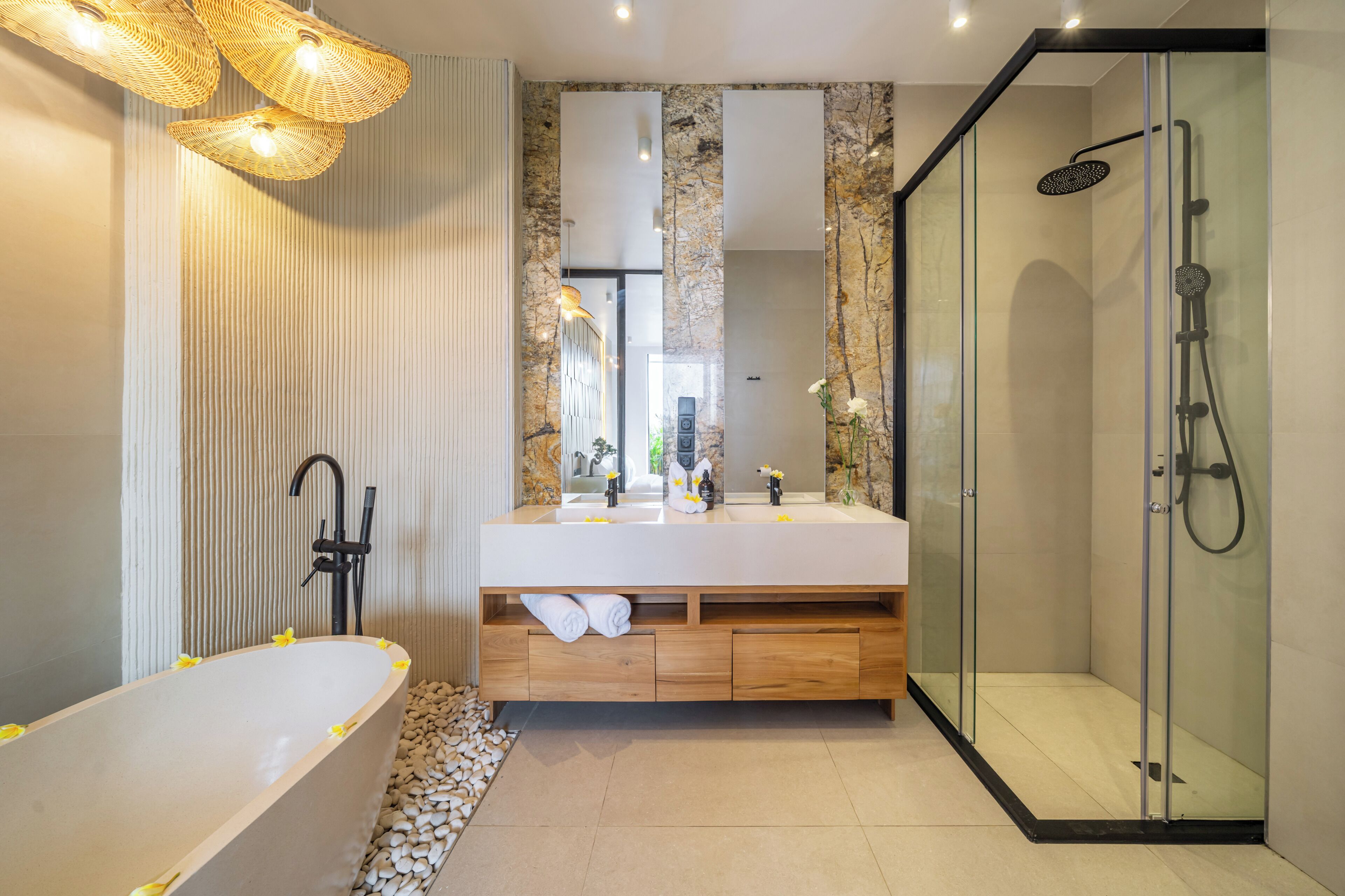 A modern bathroom with a freestanding bathtub, a glass-enclosed shower, a large mirror, and a wooden vanity.