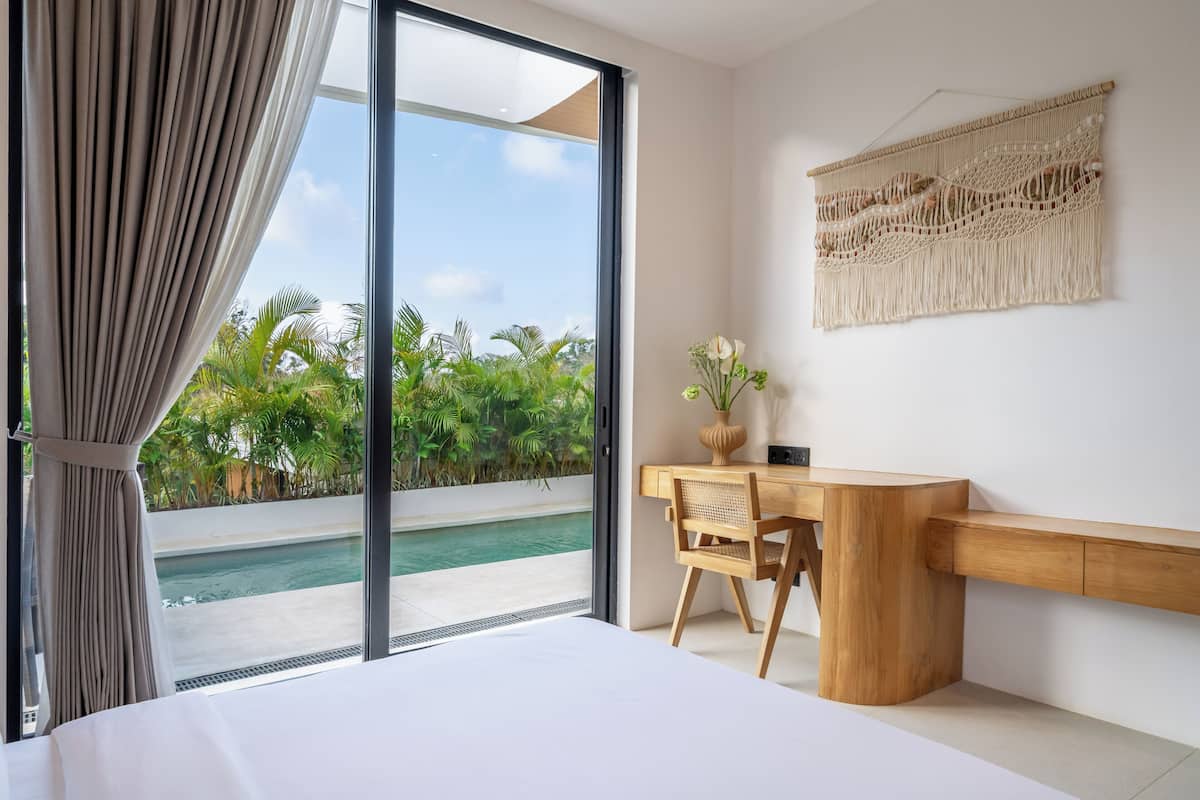 Un dormitorio con cama, escritorio y vista a una piscina.