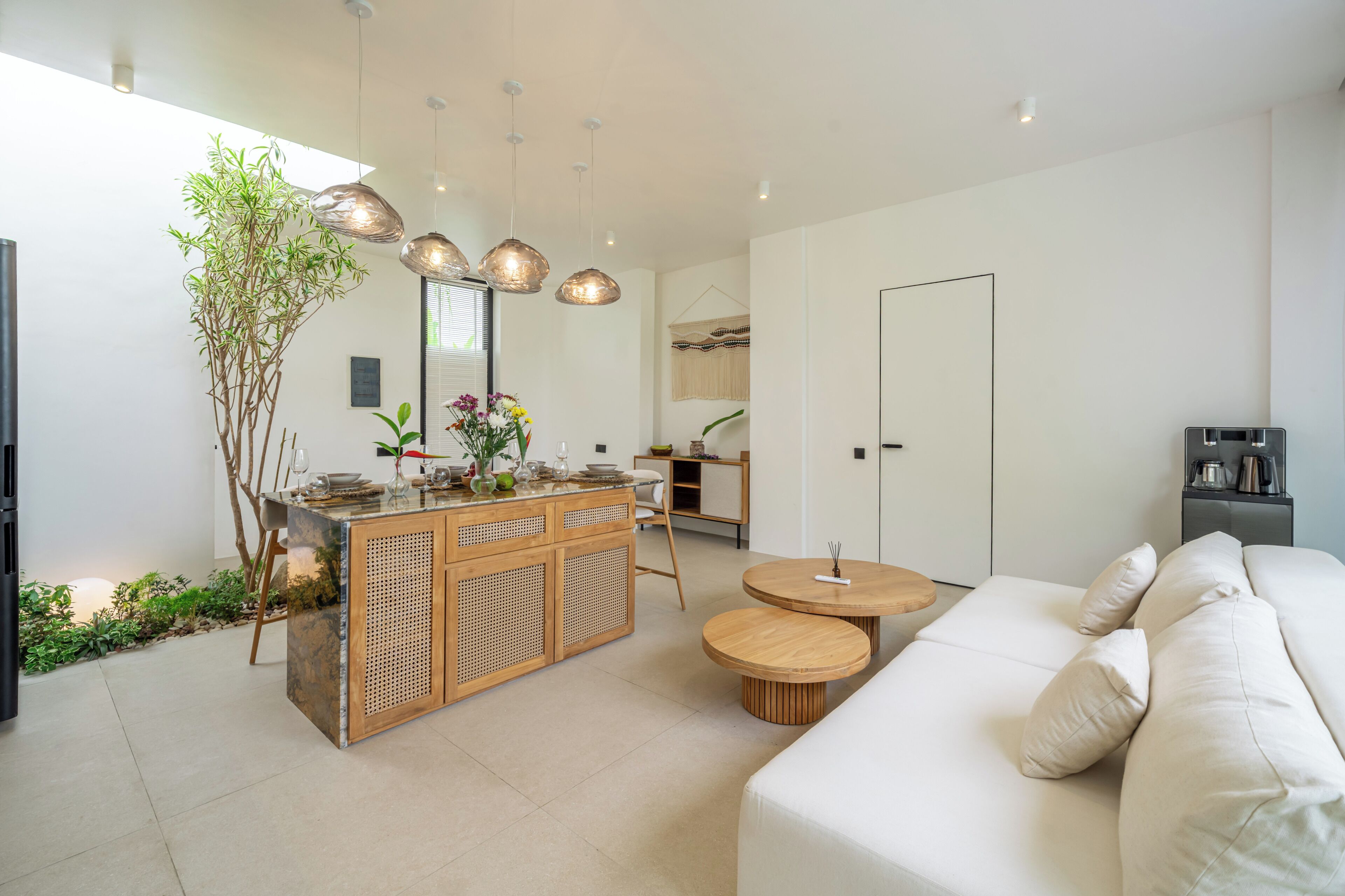 A modern kitchen with a central island, wooden furniture, and pendant lighting.