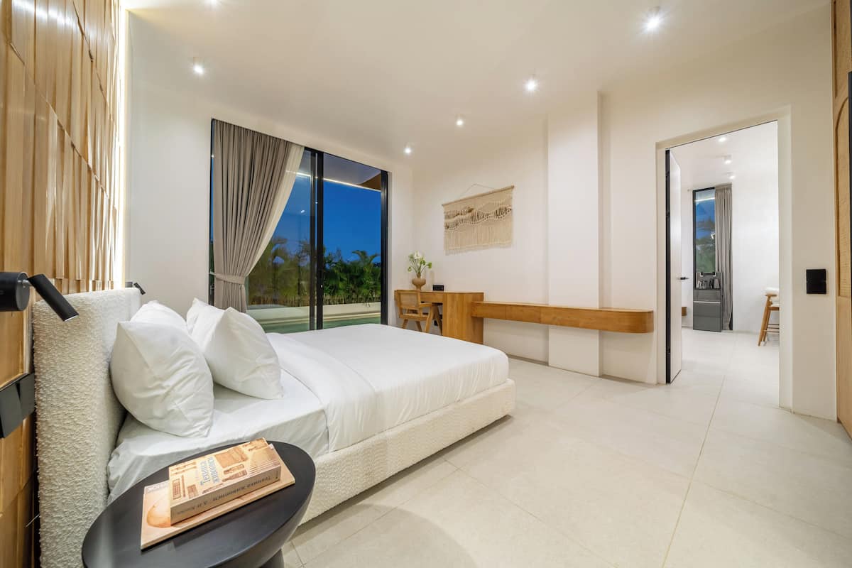 Un dormitorio moderno con una cama grande, un escritorio y vistas al exterior.