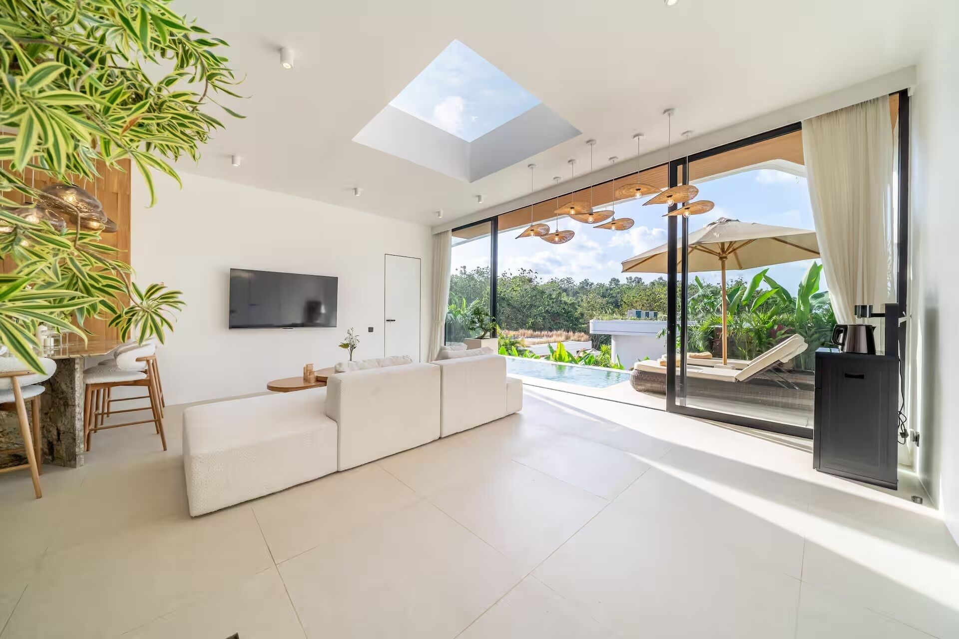 A modern living room with a large TV, a sofa, and a dining area with a table and chairs.