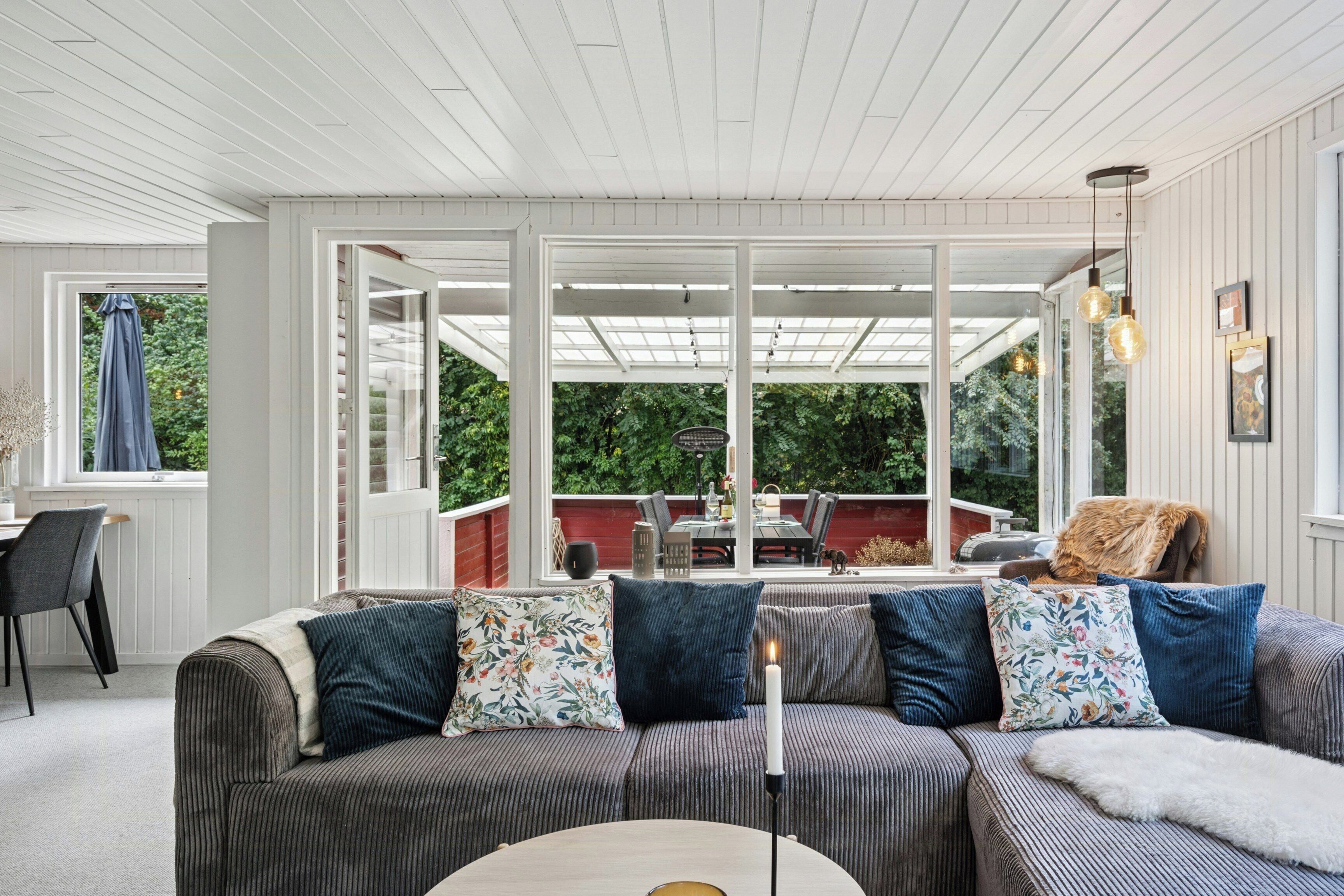 A room with a sofa, a table, and a view of an outdoor patio.