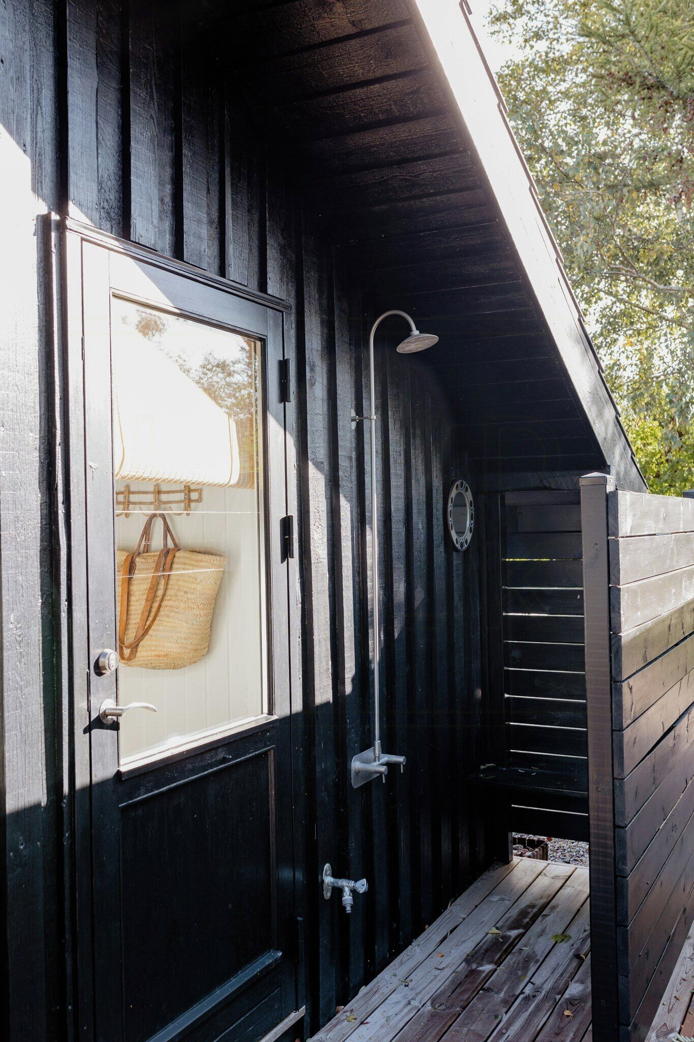 Une cabane en bois avec une porte en verre, une douche et un petit porche.