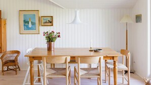 Ein Holztisch mit sechs Stühlen, eine Vase mit Blumen und zwei gerahmte Bilder an der Wand.