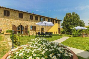 A stone building with a garden, outdoor seating, and a flag. - Lovely apartment with pool in Chianti (Montaione)