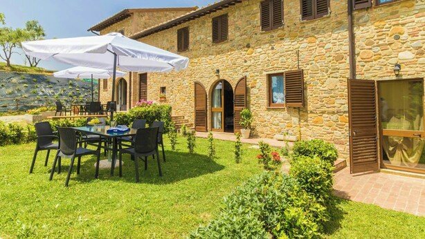 Ein Steinhaus mit Terrasse, Außenbestuhlung und Blick ins Grüne.