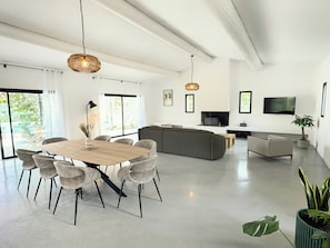 A modern living room with a dining area, large windows, a flat-screen TV, and a sofa. - Contemporary villa in the heart of the Alpilles (Eyguières,)