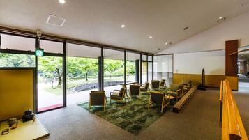 A modern interior with large windows, a green carpet, wooden furniture, and a traditional tea set.