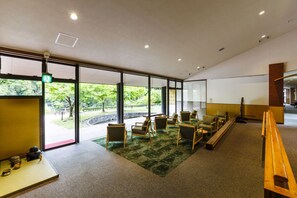 A modern interior with large windows, a green carpet, wooden furniture, and a traditional tea set.