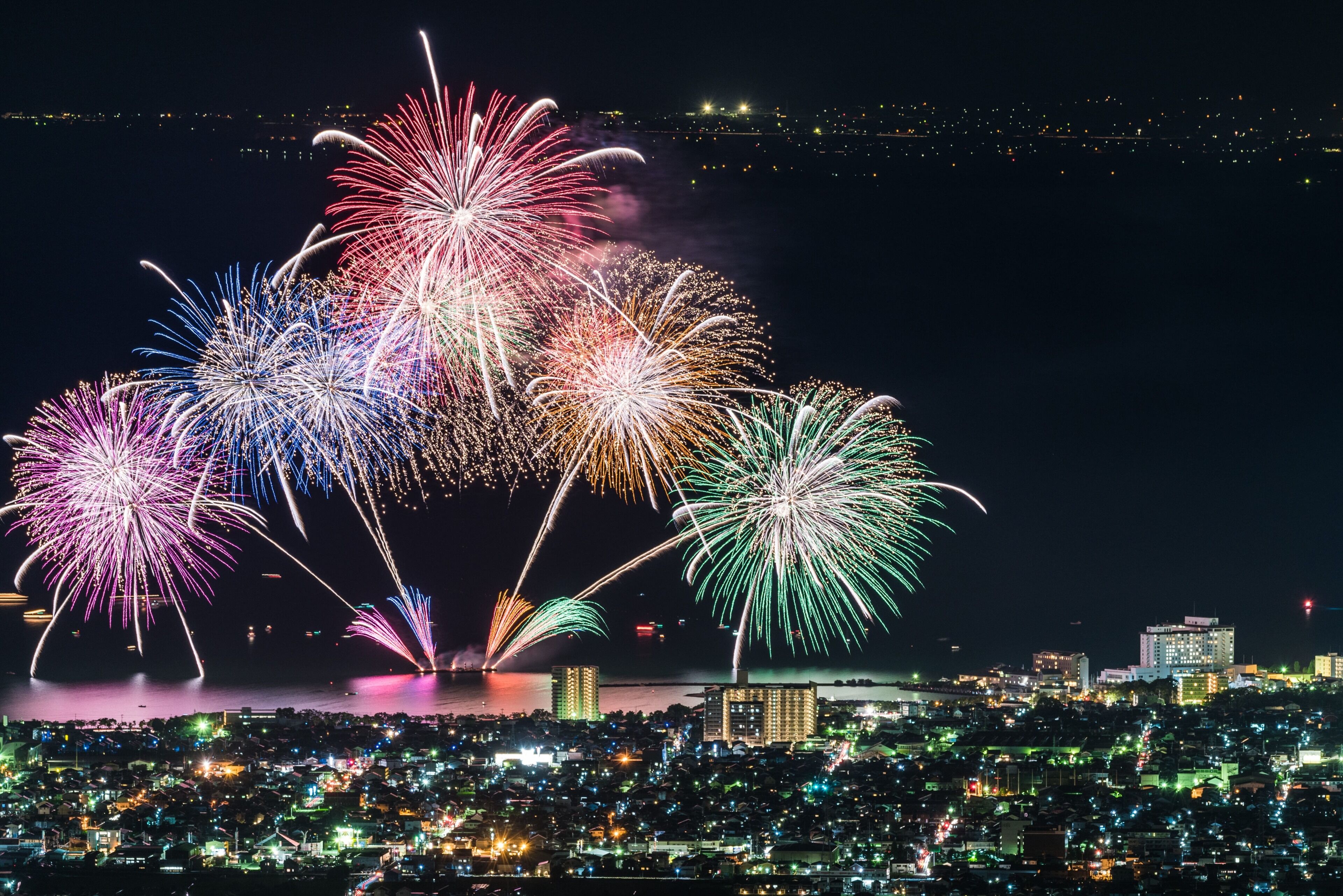 Une vue nocturne d’une ville avec un front de mer et un spectacle de feux d’artifice.
