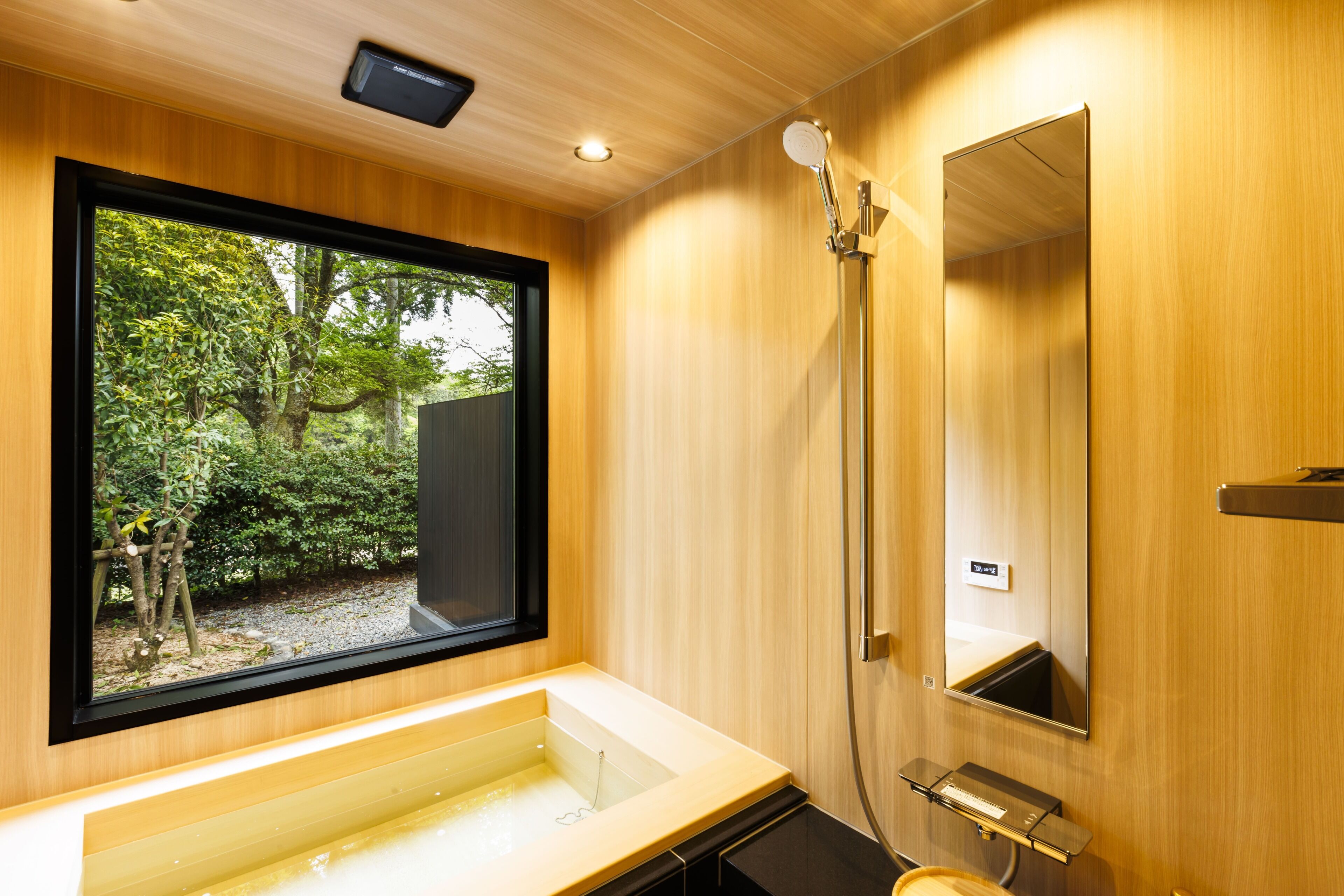 A modern bathroom with a large window, a bathtub, a shower, and a mirror.