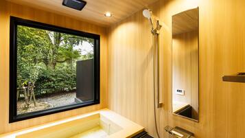 A modern bathroom with a large window, a bathtub, a shower, and a mirror.