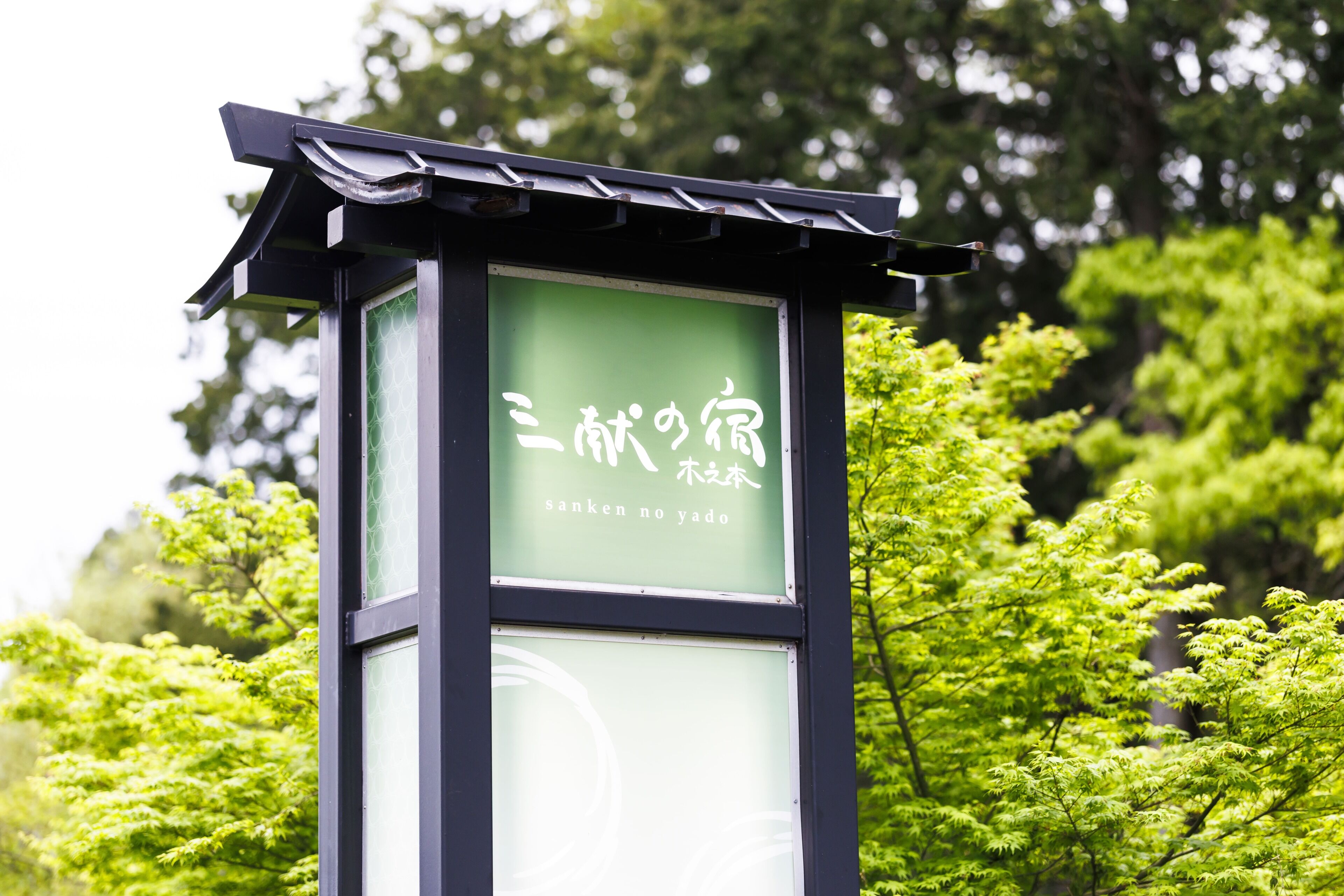 A traditional Japanese-style building with a green signboard displaying Japanese characters and English text.