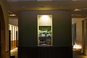 A bar area with a counter and shelves of bottles, located in a hallway with wooden paneling and a carpeted floor. - sankennoyado kinomoto (Nagahama)