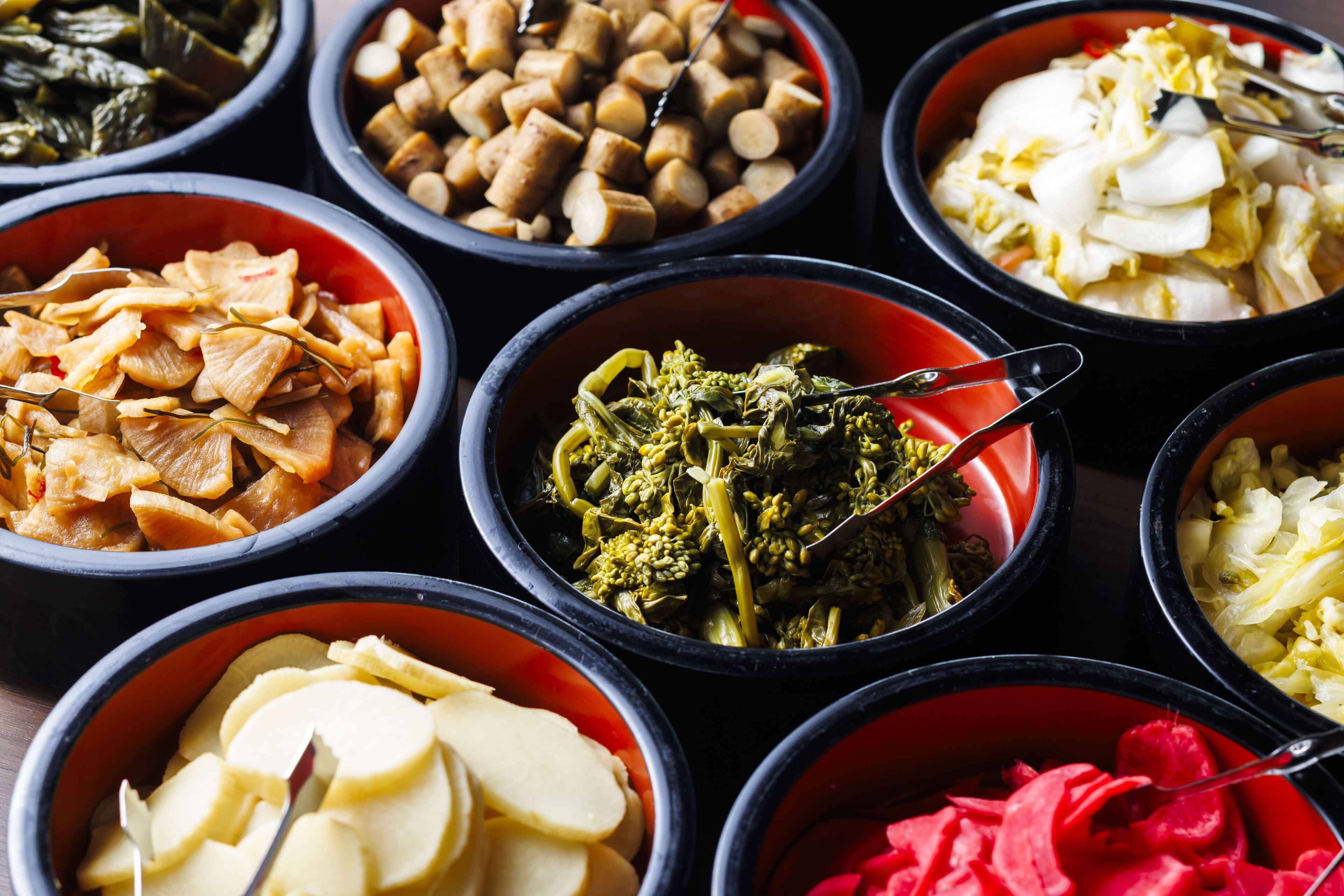 A variety of food items in bowls, including what appears to be kimchi, bean sprouts, and sliced vegetables.
