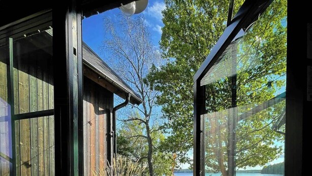 Une terrasse en bois avec un lit et une table, donnant sur un lac.