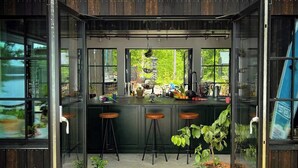 Une cuisine moderne avec une porte en verre, un plancher en bois et des plantes en pot.