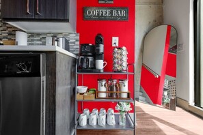A kitchen with a coffee bar, a dishwasher, a coffee maker, and a shelf with jars and cups. - 3 Story Loft. Pool. Mins to Broadway. Gym. Parking (Nashville)