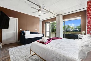 Ein Schlafzimmer mit einem großen Bett, einem Deckenventilator, einem Fenster mit Blick und einer Tür mit Jalousien.