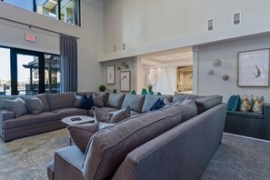 A modern living room with a sectional sofa, a coffee table, and a dining area with a chandelier. - 3 Story Loft. Pool. Mins to Broadway. Gym. Parking (Nashville)