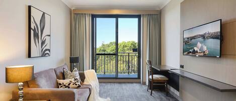 Une chambre d’hôtel avec un balcon, un canapé, un bureau et une télévision.