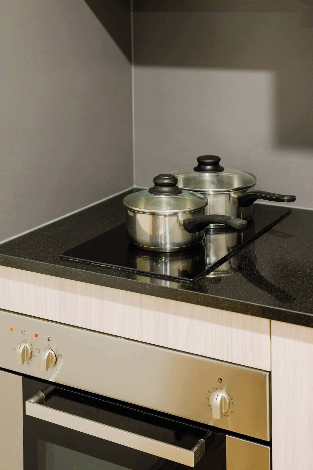 Una cocina con estufa, ollas y horno empotrado.