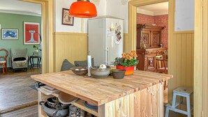 Een keuken met een houten kookeiland, een koelkast en een eethoek met een houten kast en stoelen.