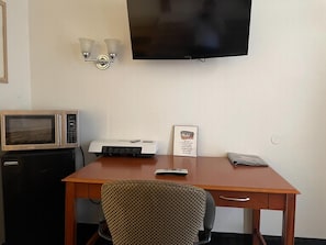 A hotel room with a wooden desk, a microwave, a printer, a television, and a framed sign on the wall. - Kiteville Cordes Lakes Motel & RV Park (Cordes Lakes)