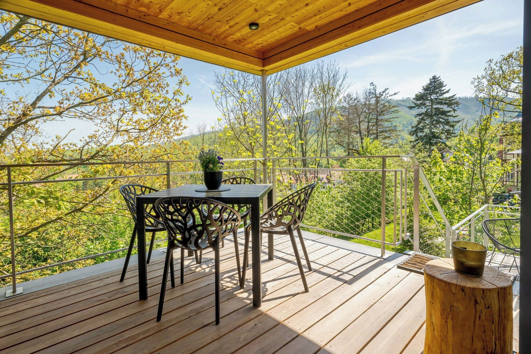 Eine Holzdielen-Terrasse mit Tisch und Stühlen mit Blick auf eine Berglandschaft.