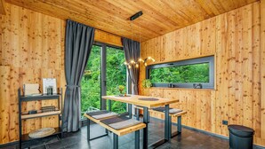 A modern wooden interior with a dining area, large windows, and a view of greenery. - Treetop house near Mount Brocken (Ilsenburg)