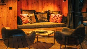 A cozy interior with a wooden wall, a sofa with cushions, and two chairs around a table. - Treetop house near Mount Brocken (Ilsenburg)