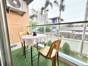 A balcony with a table, chairs, and a fan. - cozy studio unit laguna 2 (Muang Pattaya)