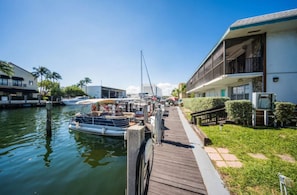 Un puerto deportivo con barcos amarrados, un muelle de madera y un edificio con balcones.