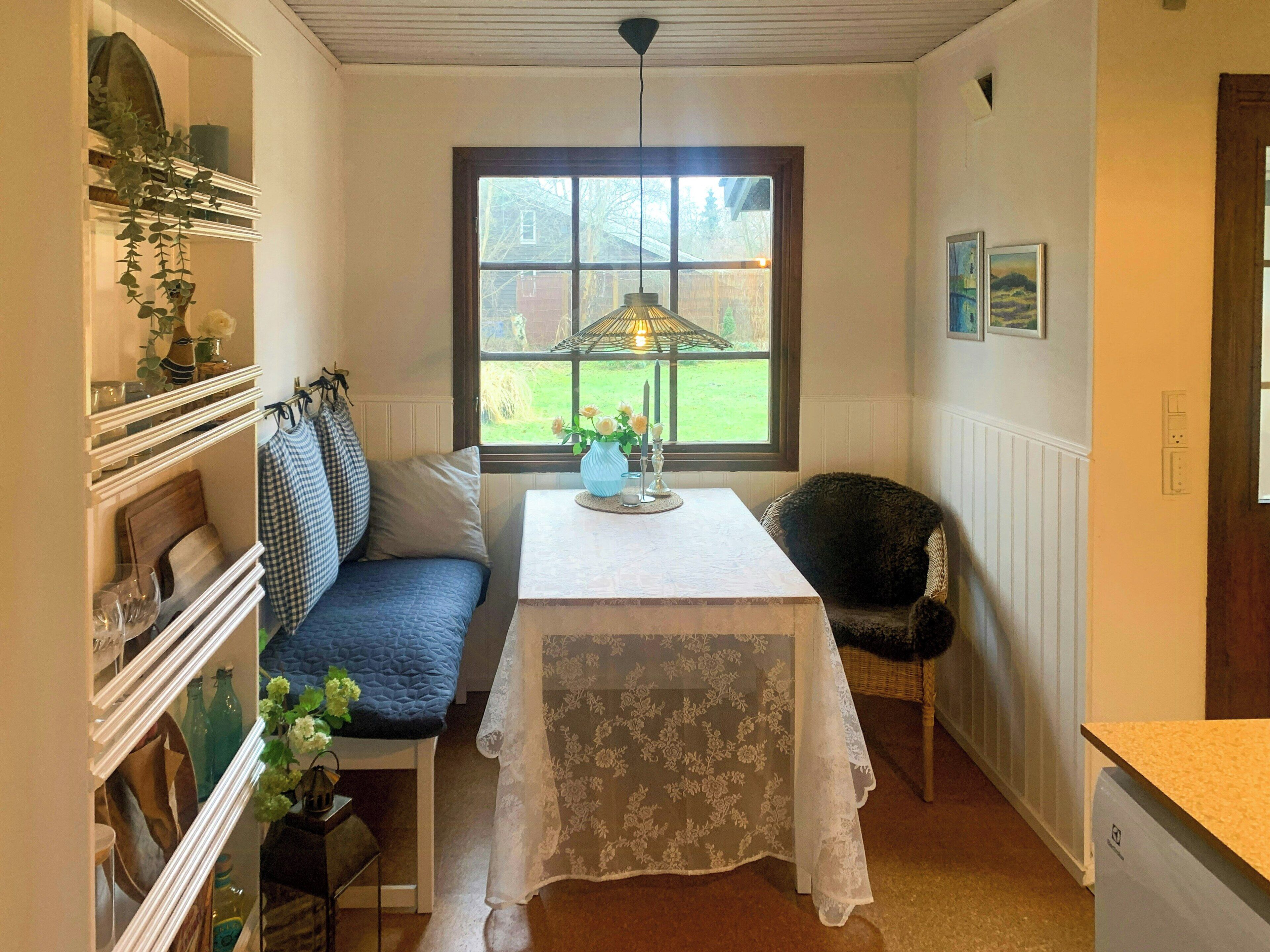 Una habitación con una mesa, banco y ventana.