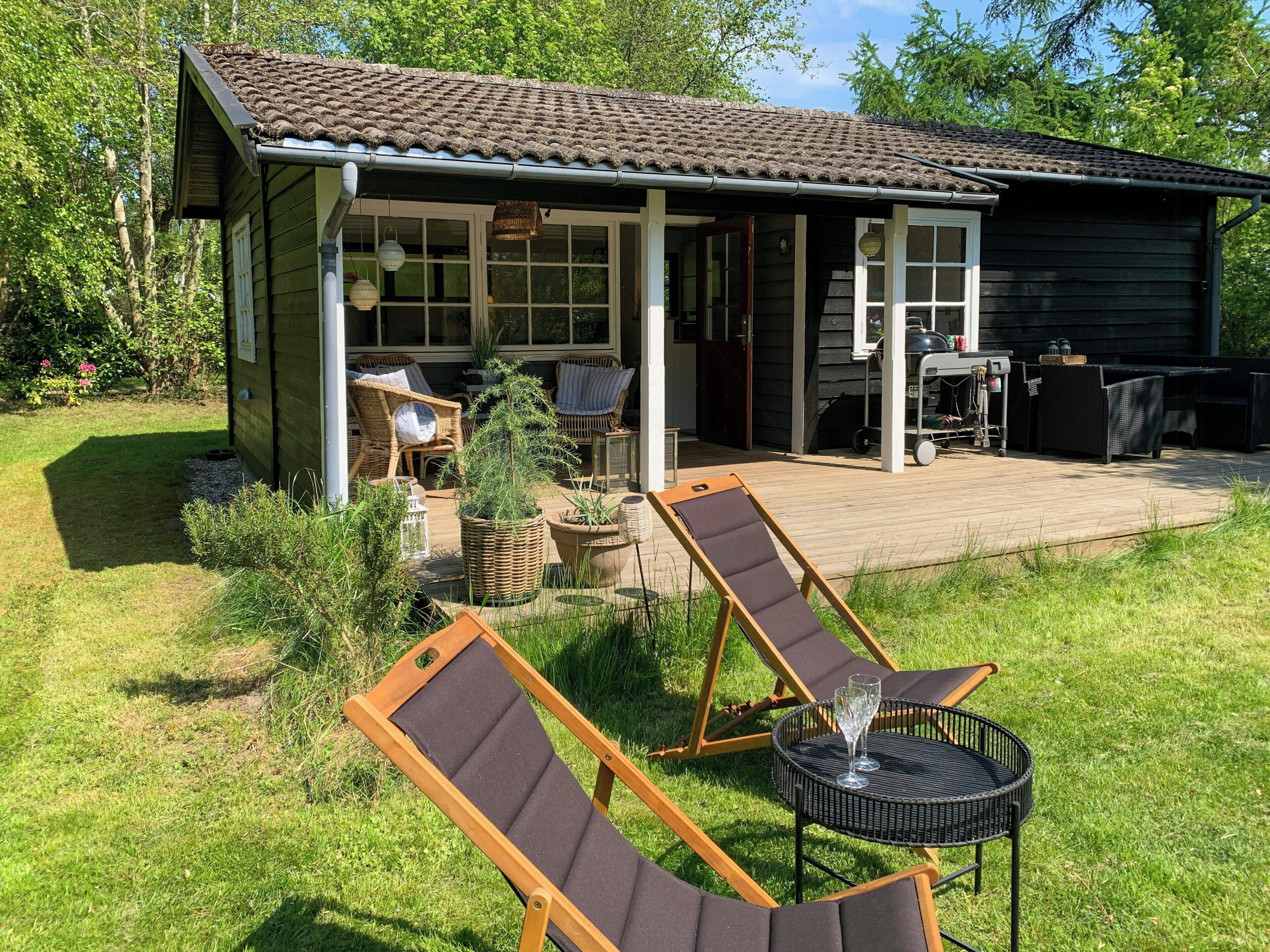 Une cabane en bois dotée d’une terrasse, d’un espace salon extérieur et d’un petit jardin.