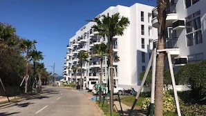 A multi-story residential building with balconies, a clear sky, and a sidewalk. - Serene 1-bedroom Apartment in Boracay With Pool Access (Boracay Island)