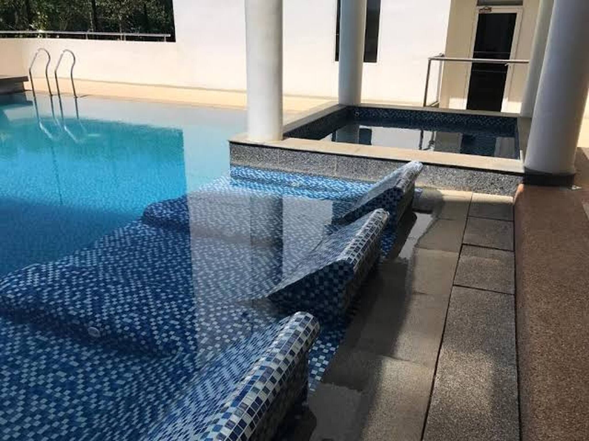 Piscina com borda azulejada, área ao redor da piscina e vista do céu.