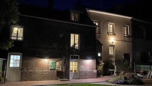 A two-story building with a brick facade, a visible garage door, and a well-lit entrance. - Charming house by the Seine in Normandy (Poses)