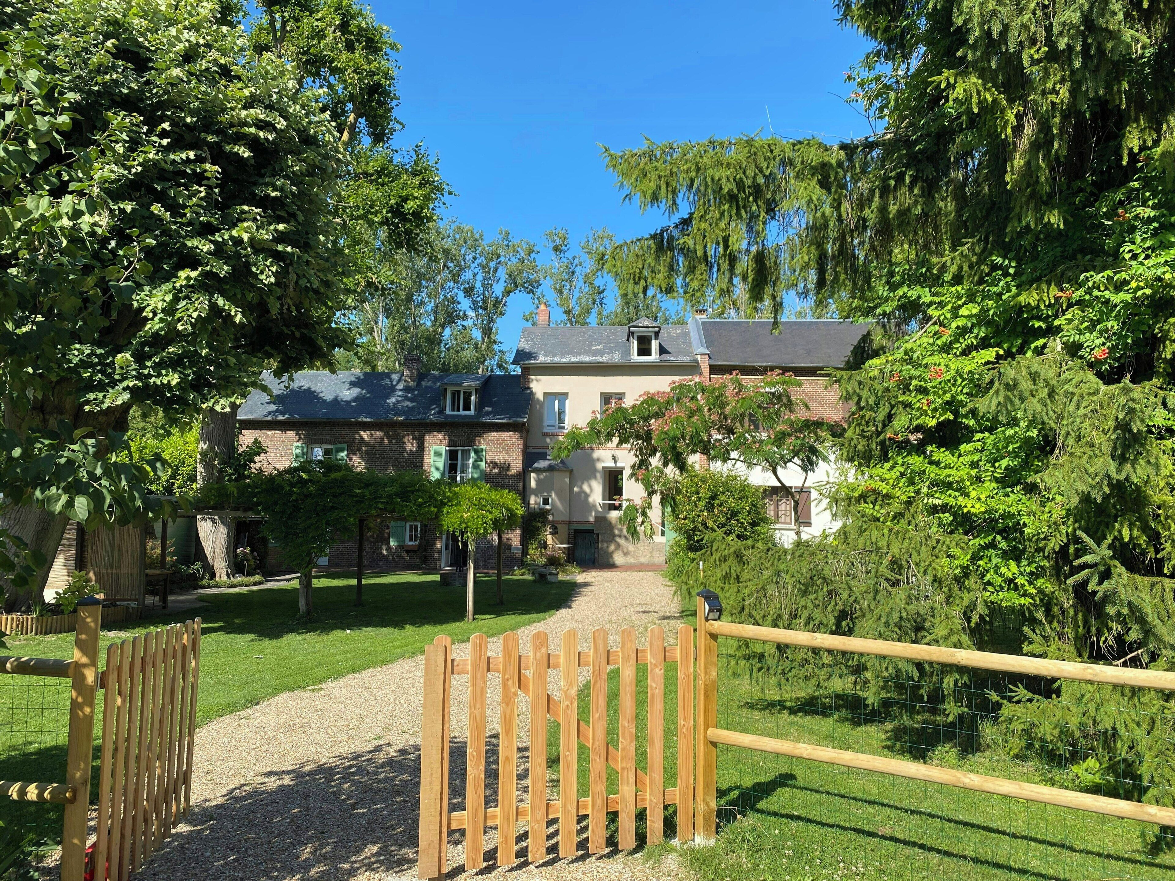 A pathway leading to a building with a brick facade, surrounded by lush greenery and trees.