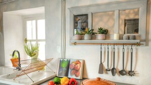 A kitchen with a window, a hanging pot rack, a sink, and various kitchen utensils. - Riverside house with farm animals in Béarn (Autevielle-Saint-Martin-Bideren)
