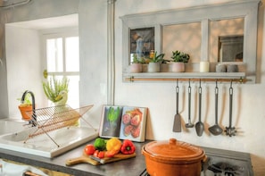 A kitchen with a window, a hanging pot rack, a sink, and various kitchen utensils. - Riverside house with farm animals in Béarn (Autevielle-Saint-Martin-Bideren)